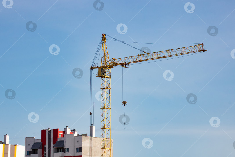 Скачать Строительный кран и высокие дома на фоне голубого неба фотосток Ozero