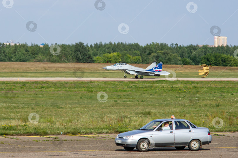 Скачать Российский истребитель МиГ-35 поколения "четыре плюс" (НАТО-Fulcrum) движется по взлетно-посадочной полосе после посадки. Автомобиль движется по рулежной дорожке. Размытый фон. Выборочный фокус. фотосток Ozero