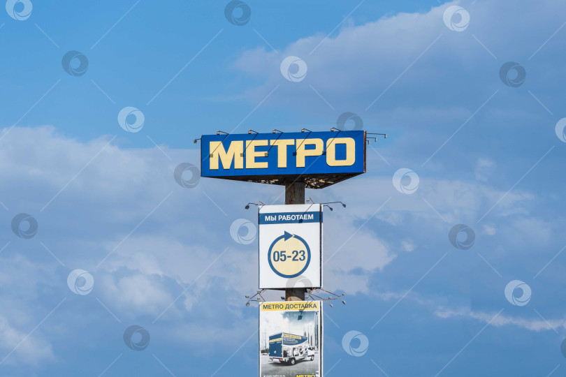 Скачать Высокий рекламный столб перед входом на парковку Metro Cash and Carry. На почте размещена информация о часах работы, доставке товаров и оптовой торговле. Краснодар, Россия - 19 мая 2022 года. фотосток Ozero