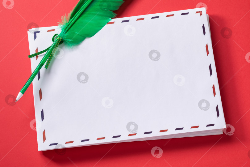 Скачать Стопка белых поздравительных конвертов с пером в форме ручки на красном фоне, шаблон для дизайнера фотосток Ozero