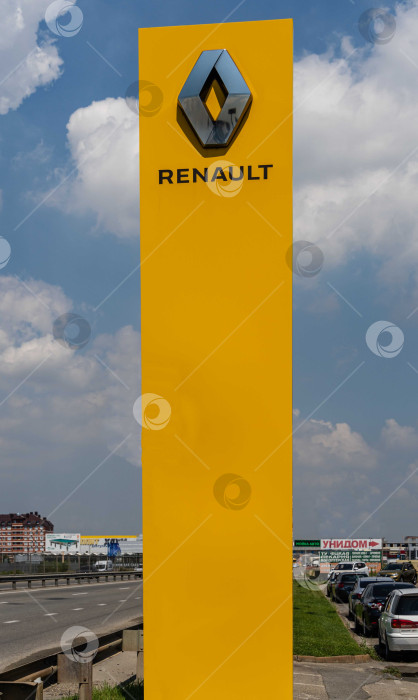 Скачать Логотип автопроизводителя Renault на желтом вертикальном пилоне. Пилон с логотипом между шоссе и автостоянкой перед сервисным центром Renault в Адыгее. фотосток Ozero