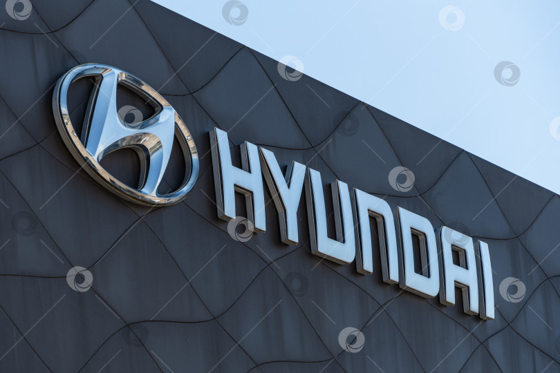 Скачать Логотип автопроизводителя Hyundai и надпись Hyundai на фасаде дилерского центра Hyundai. Надпись с логотипом на коричневом фоне. Сервисный центр в Адыгее. фотосток Ozero