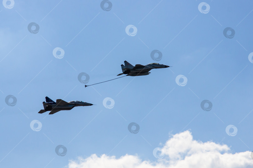 Скачать Российский многоцелевой истребитель четвертого поколения МиГ-29 и истребитель "четыре с плюсом" (НАТО-Fulcrum) МиГ-35 демонстрируют дозаправку в воздухе над аэродромом. Крупный план. фотосток Ozero