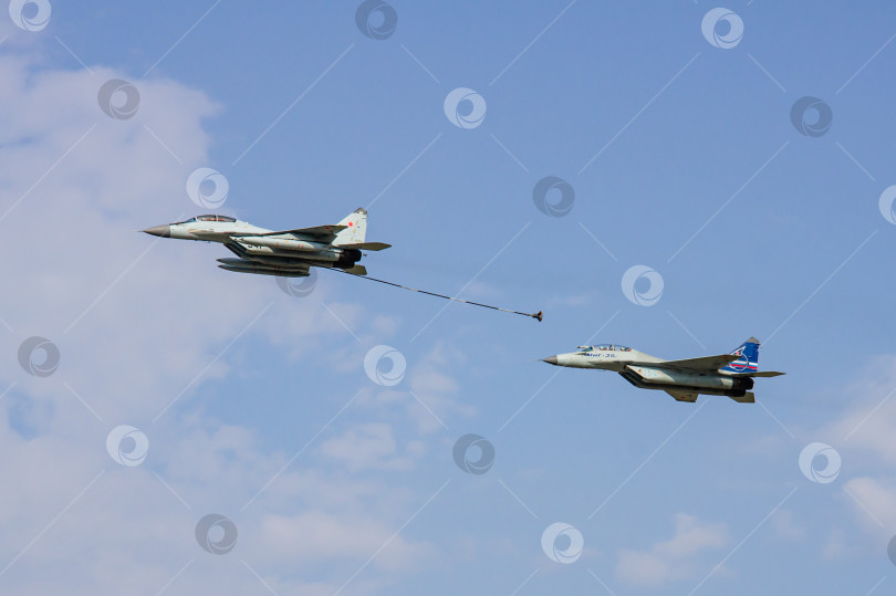 Скачать Российский многоцелевой истребитель четвертого поколения МиГ-29 и истребитель "четыре с плюсом" (НАТО-Fulcrum) МиГ-35 демонстрируют дозаправку в воздухе над аэродромом. Крупный план. фотосток Ozero