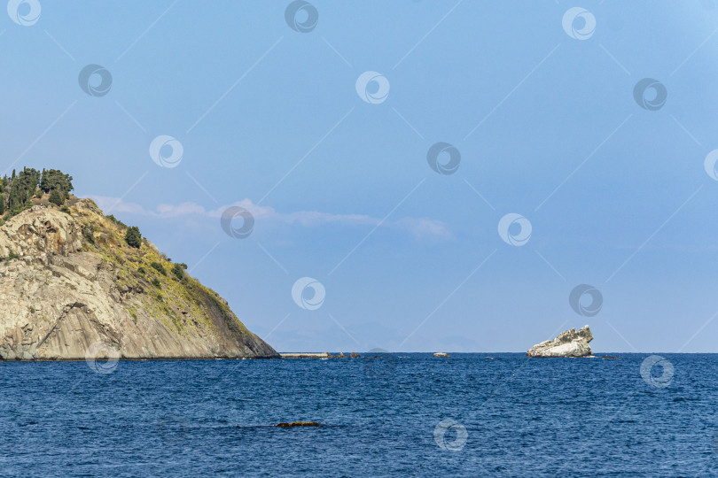 Скачать Вид на спокойное синее море. Береговая линия с утесами и горами, поросшими вечнозелеными растениями. Бирюзовая морская вода сливается с горизонтом и переходит в голубое безоблачное небо. Концепция природы для дизайна фотосток Ozero