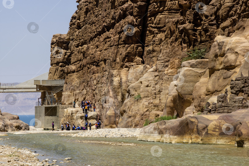 Скачать Иордания. Вади Муджиб. Единственный мост Муджиб пересекает реку Вади Муджиб. Отвесные скалы огромной высоты и река Вади Муджиб. Группа туристов спускается в ущелье. Вади Муджиб, Иордания, 21 мая 2011 г. фотосток Ozero