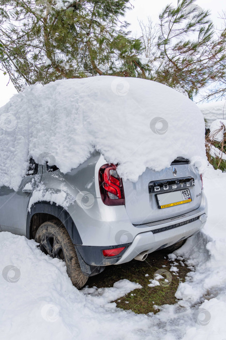 Скачать Приключенческий автомобиль Renault Duster припаркован под огромным сугробом. Крупный план. Сугробы на крыше автомобиля после сильного ночного снегопада. Экстремальные сугробы на юге России. фотосток Ozero