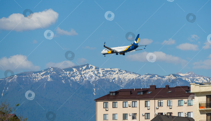 Скачать Boeing 737-900ER Azur Air заходит на посадку в аэропорту Адлера над зданиями на побережье горной реки Мзымта на фоне Кавказских гор. Адлер Сириус, Россия - 18 мая 2021 г. фотосток Ozero