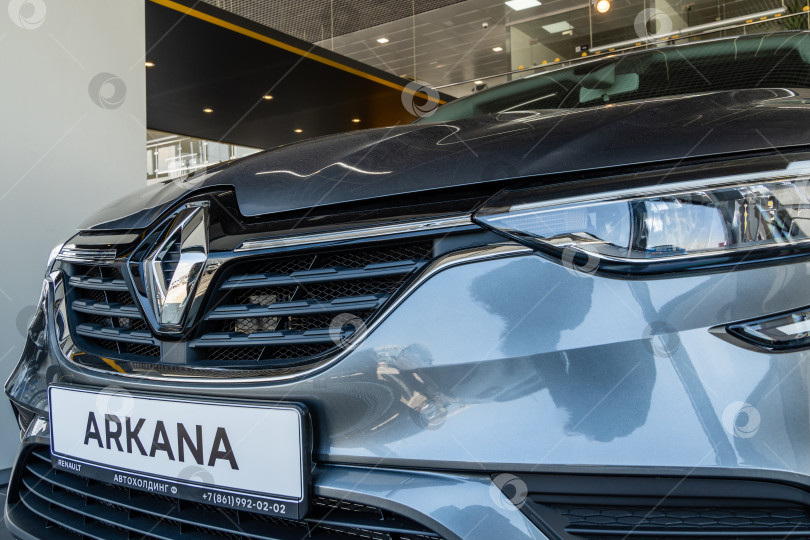 Скачать Крупный план решетки радиатора с логотипом Renault и капота внедорожника Renault Arkana в демонстрационном зале дилерского центра Renault. Вид слева. Мега Адыгея. фотосток Ozero