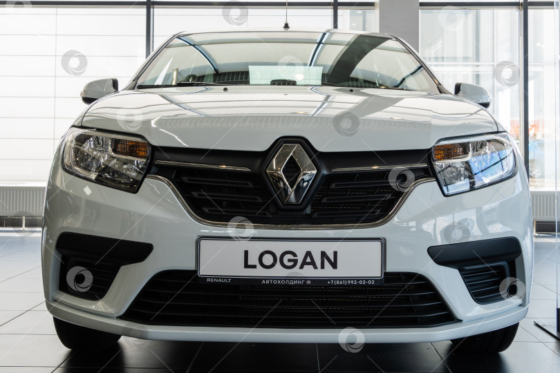 Скачать Вид спереди на белый автомобиль Renault Logan в автосалоне дилерского центра Renault. Автомобиль крупным планом. Автосалон Renault в Мега Адыгея. фотосток Ozero