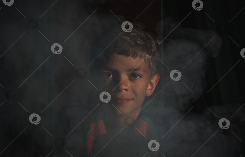 Скачать Маленький мальчик сидит у дымящегося костра фотосток Ozero