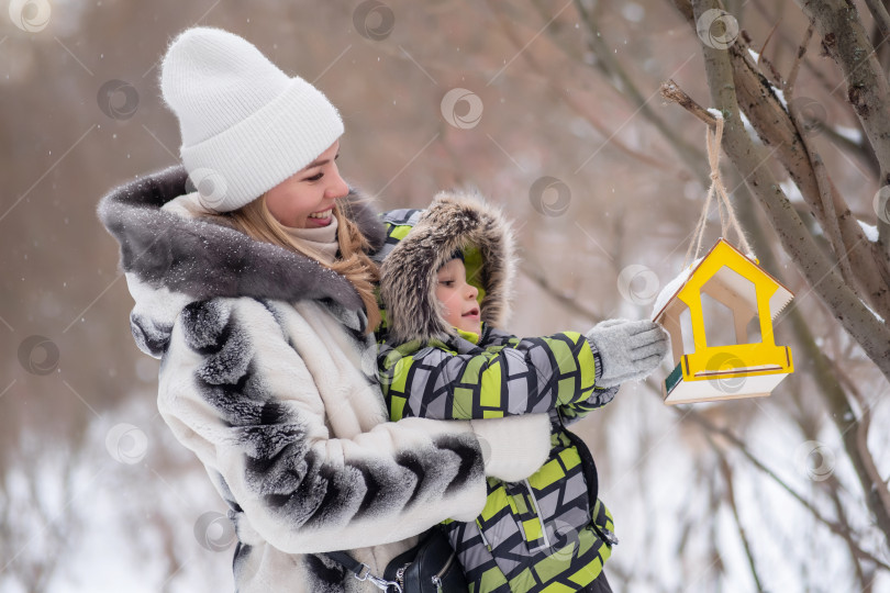 Скачать мать и сын в зимнем парке кормят птиц с помощью кормушки фотосток Ozero