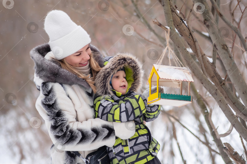 Скачать мать и сын в зимнем парке кормят птиц с помощью кормушки фотосток Ozero