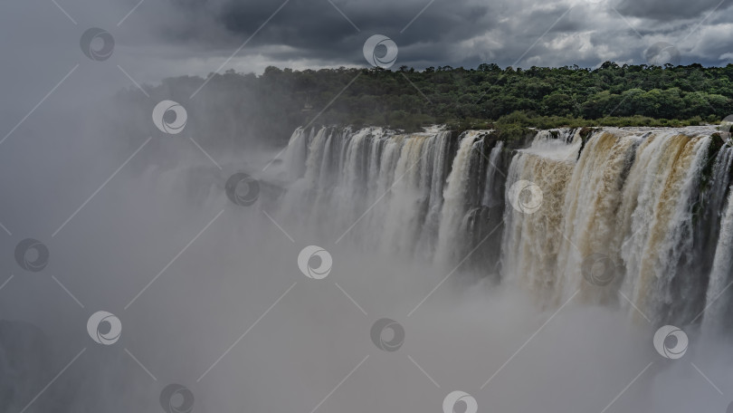 Скачать Мощные потоки водопада низвергаются с выступа скалы в пропасть. фотосток Ozero