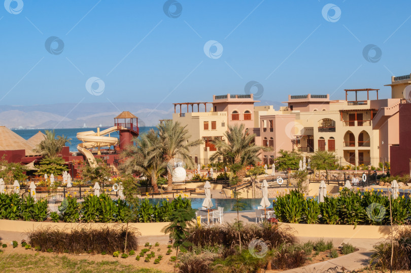 Скачать Иордания. Акаба. "Отель Movenpick Resort and SPA Tala Bay Aqaba 5 звезд" на берегу Красного моря. Территория отеля с множеством бассейнов окружена пальмами и другими экзотическими растениями. фотосток Ozero