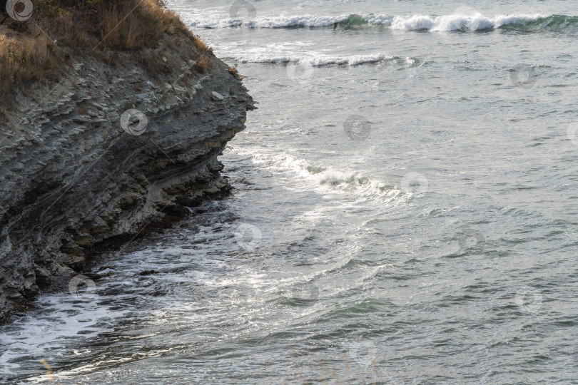 Скачать Белые волны разбиваются о скалистый берег Черного моря в Геленджике. Белые брызги и пена на переднем плане. Изумрудно-голубая морская вода. Сентябрьское море на южном курорте России. фотосток Ozero