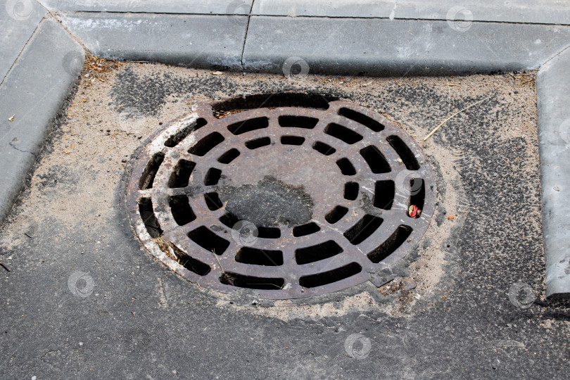 Скачать Крышка канализационного люка на тротуаре крупным планом фотосток Ozero