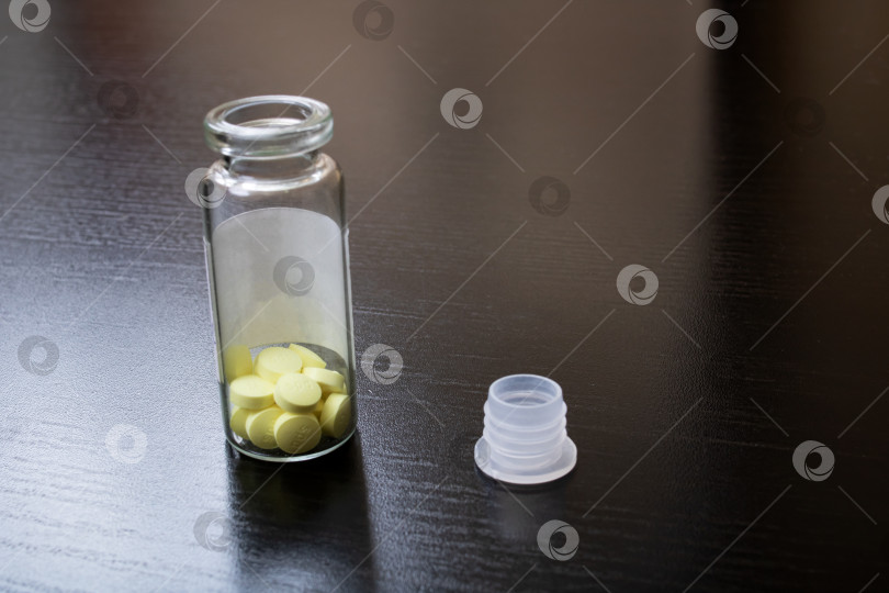 Скачать Желтые таблетки в открытой стеклянной банке на столе фотосток Ozero