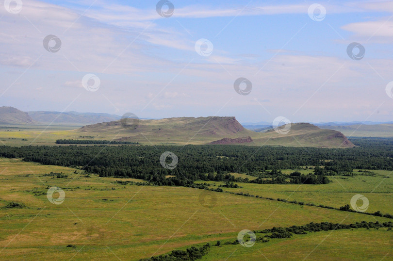 Скачать Панорамный снимок бескрайней степи и леса у подножия высоких скалистых холмов. фотосток Ozero