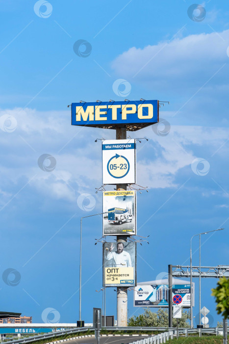 Скачать Высокий рекламный столб перед входом на парковку Metro Cash and Carry. На почте размещена информация о часах работы, доставке товаров и оптовой торговле. Краснодар, Россия - 19 мая 2022 года. фотосток Ozero