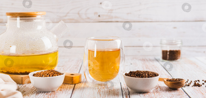 Скачать Свежий гречневый чай в стакане, заварочном чайнике и гранулах в миске на столе веб-баннер фотосток Ozero
