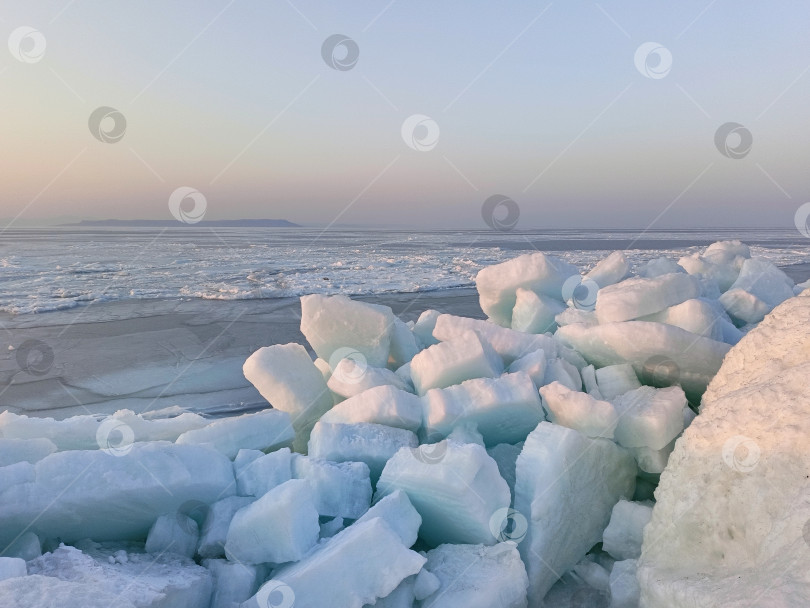 Скачать Глыбы льда на берегу замерзшего моря в лучах розового заката фотосток Ozero