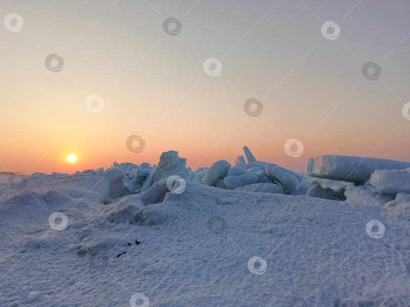 Скачать Глыбы льда на берегу замерзшего моря в лучах оранжевого заката фотосток Ozero