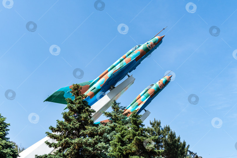 Скачать Два самолета МиГ-21МФ на постаменте на фоне голубого осеннего неба. Крупный план. Два боевых сверхзвуковых самолета были установлены на постаменте в начале 80-х годов прошлого века. фотосток Ozero