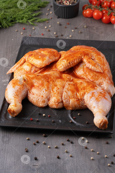 Скачать Цельная куриная тушка с приправами на черном блюде для вашего мясного меню или оформления буклета фотосток Ozero