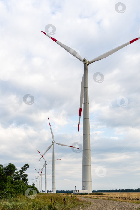 Скачать Башни ветряных турбин с вращающимися лопастями на закате на фоне облачного неба. Крупный план. Адыгейская ветроэлектростанция из множества башен ветряных турбин в полевых условиях. Ветроэнергетический комплекс Росатома. фотосток Ozero