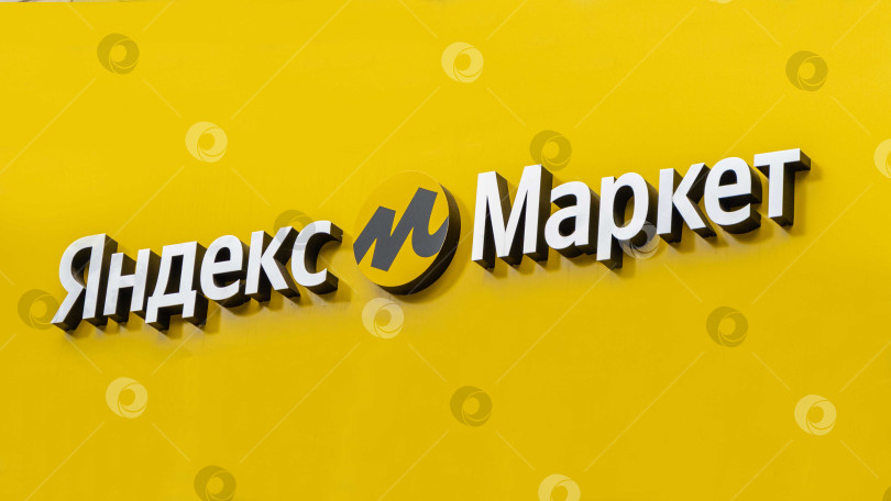 Скачать Логотип Яндекс Маркета на желтом фоне над входом в здание. Логотип интернет-магазина - буква "М" в центре желтого круга. Надпись "Яндекс Маркет" на русском языке. фотосток Ozero