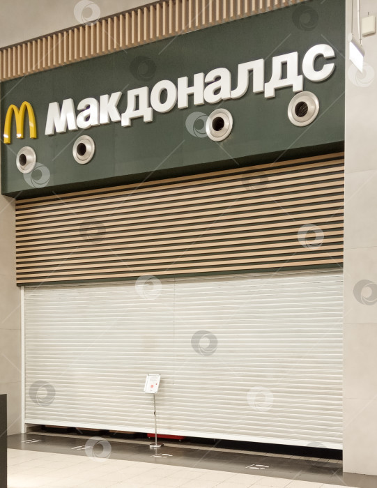 Скачать Ресторан McDonald's в торговом центре "Мега Адыгея" был закрыт из-за санкций. Над опущенными рольставнями - название и логотип McDonald's. Крупный план. фотосток Ozero