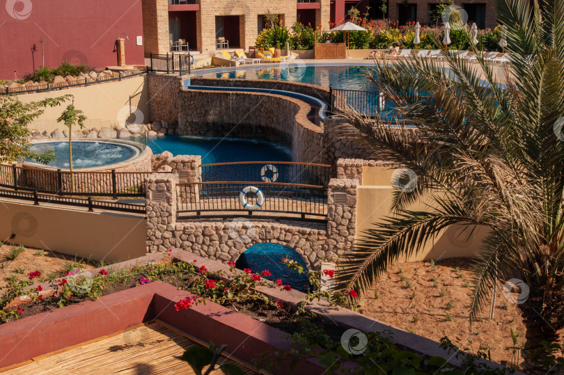 Скачать Иордания. Акаба. "Отель Movenpick Resort and SPA Tala Bay Aqaba 5 звезд" на берегу Красного моря. Территория отеля с множеством бассейнов окружена пальмами и другими экзотическими растениями. фотосток Ozero