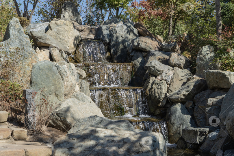 Скачать Краснодарский "Японский сад". Каскадный водопад со множеством ступеней. Искусственное каменное русло искусственной реки на размытом фоне зелени. Выборочный фокус. Парк "Краснодар" или парк Галицкого фотосток Ozero