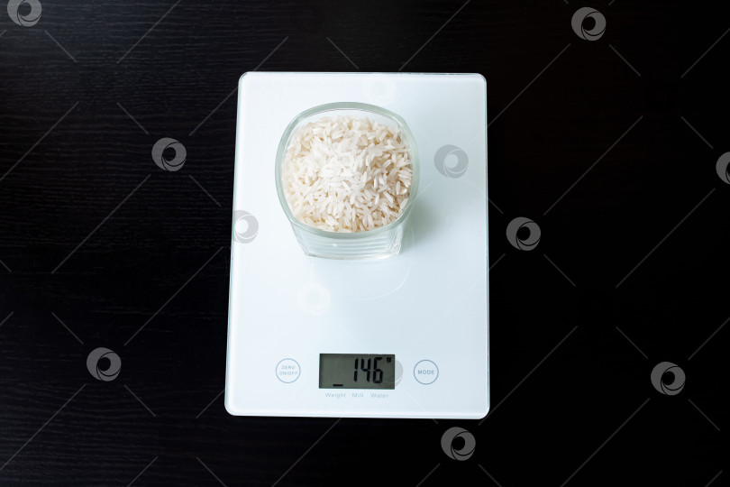 Скачать Стакан с рисом на электронных весах на деревянном столе фотосток Ozero