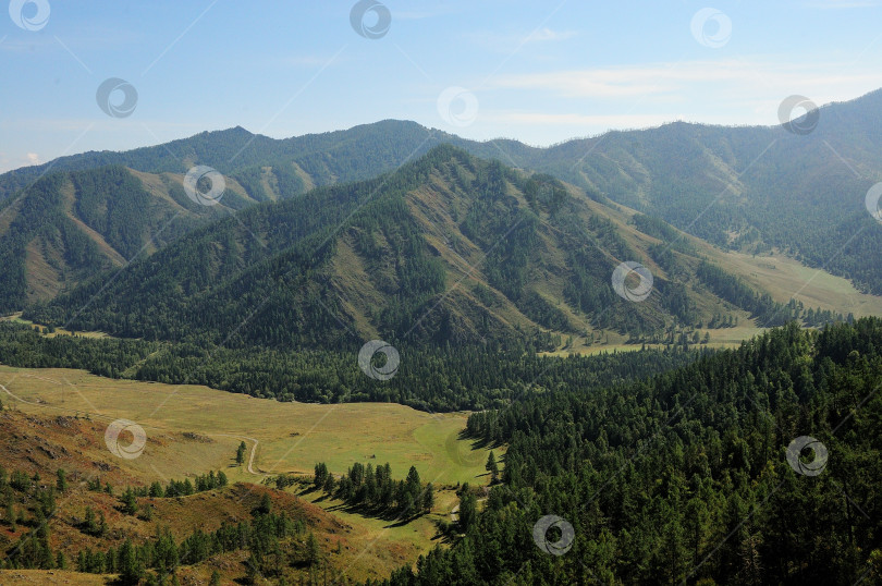 Скачать Вид сверху на живописную долину, окруженную высокими горами, покрытыми густым хвойным лесом. фотосток Ozero