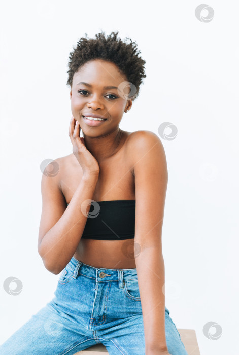 Скачать Портрет красивой молодой афроамериканки в черном топе и синих джинсах, выделенный на белом фоне фотосток Ozero
