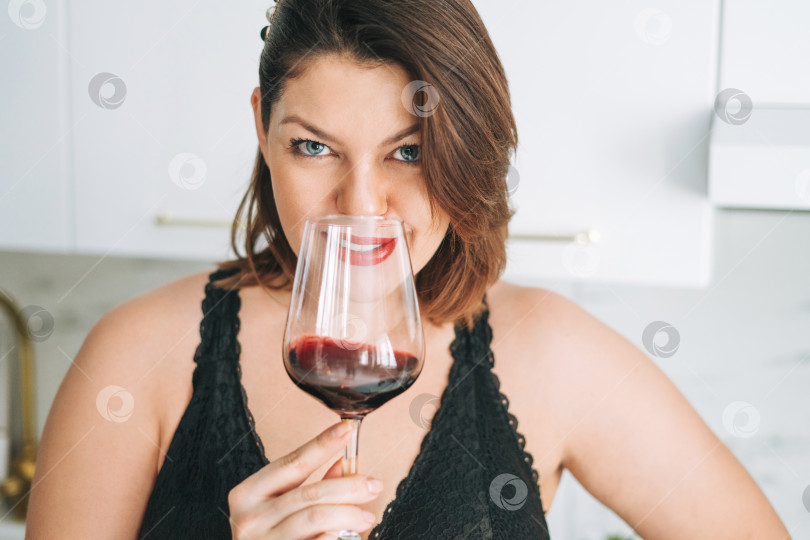 Скачать Красивая счастливая чувственная брюнетка, молодая женщина с позитивным телом плюс размер, с бокалом красного вина наслаждается своей жизнью дома фотосток Ozero