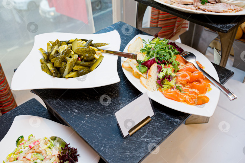 Скачать Шведский стол с солеными огурцами, салатом и копченым лососем фотосток Ozero