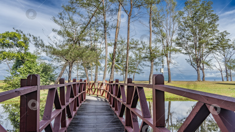 Скачать Дощатый пешеходный мост с деревянными перилами перекинут через спокойную реку. фотосток Ozero