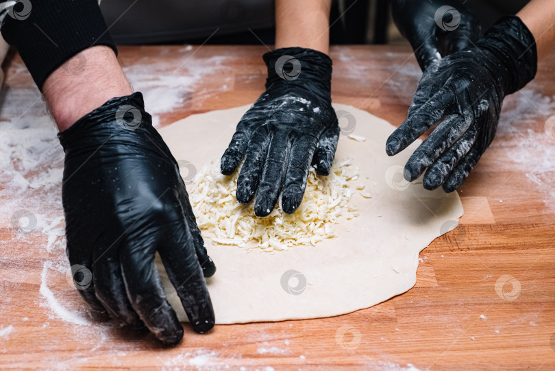 Скачать Шеф-повар готовит тесто с сырной начинкой на деревянной поверхности фотосток Ozero