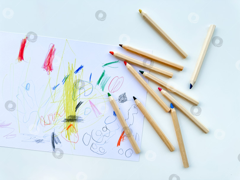 Скачать Цветные карандаши на фоне детского рисунка. Вид сверху. фотосток Ozero