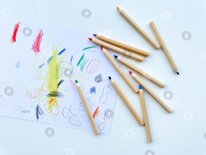 Скачать Цветные карандаши на фоне детского рисунка. Вид сверху. фотосток Ozero
