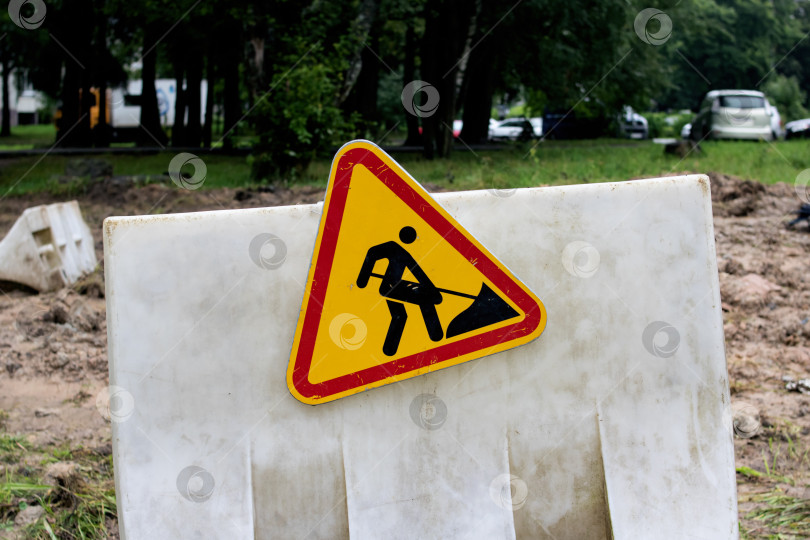 Скачать Знак строительных работ на заборе на траве фотосток Ozero