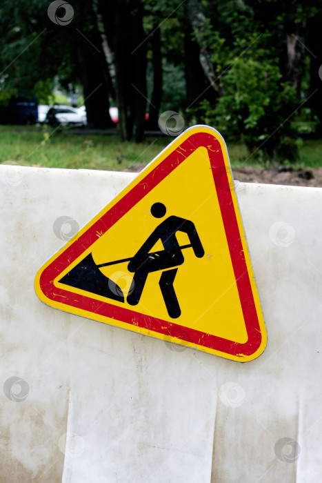 Скачать Знак строительных работ на заборе на траве фотосток Ozero