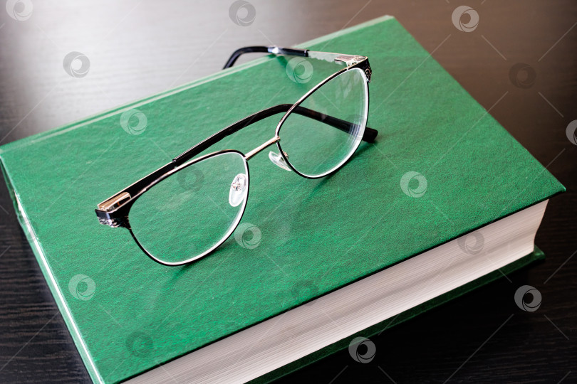 Скачать Очки и зеленая книга на деревянном столе фотосток Ozero