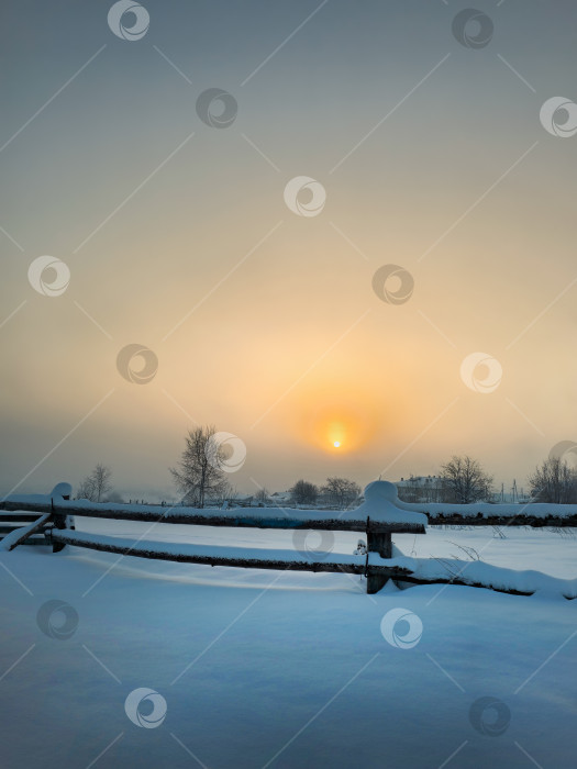 Скачать Туманный восход солнца над полем с деревянным забором и деревней фотосток Ozero