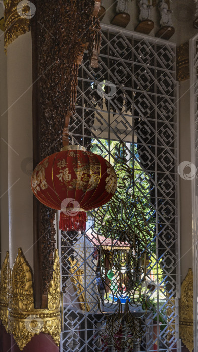 Скачать Декоративный красный китайский фонарь подвешен в храме к зарешеченному окну. фотосток Ozero