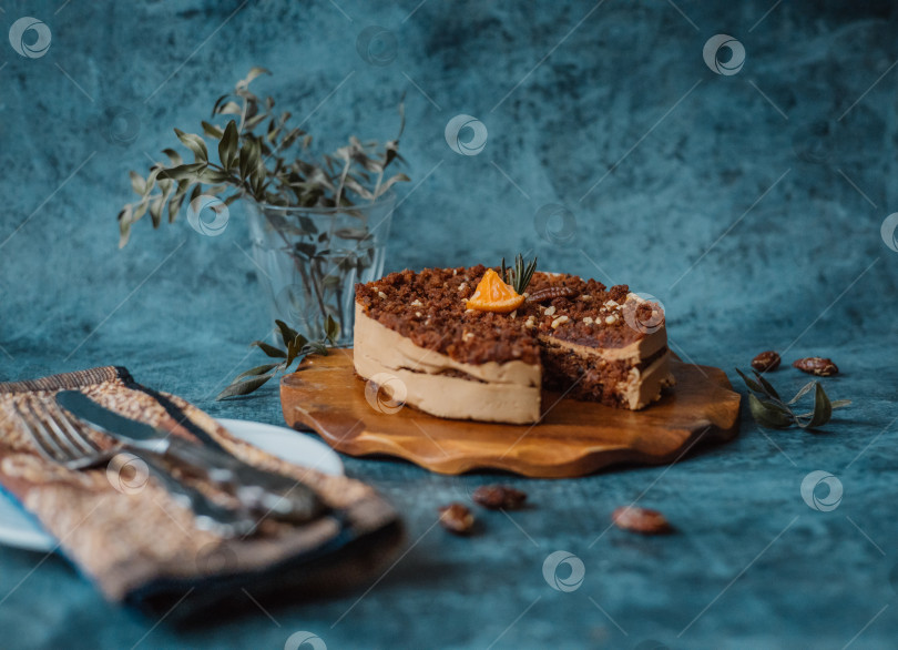 Скачать Домашний торт с шоколадом и кремом на круглой деревянной доске, тарелка с куском торта рядом с вилкой и ножом на темном фоне. Домашняя выпечка фотосток Ozero