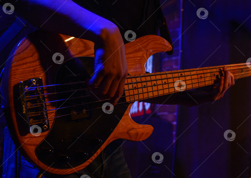 Скачать Бас-гитара в руках гитариста в атмосфере рок-бара фотосток Ozero